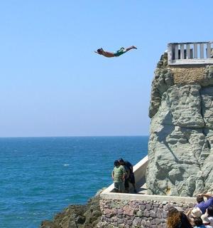 a man flying a kite on a cliff near the ocean