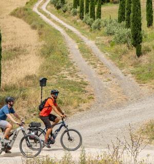two people riding bikes on a dirt road