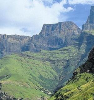 a view of a canyon with green hills and cliffs