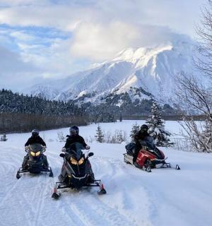 a group of four people riding on snowobiles in the snow