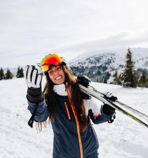 一名女子站在白雪覆盖的山坡上,手拿滑雪板