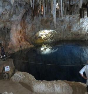 two people standing in a cave with a pool of water