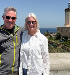 a man and woman standing in front of a lighthouse