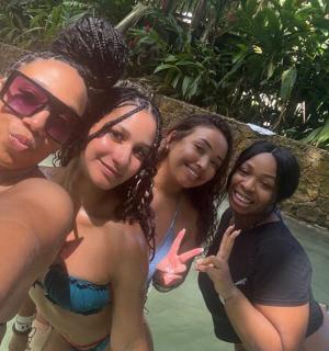a group of four women standing next to a swimming pool