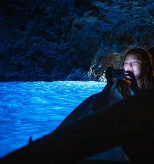 žena fotící v jeskyni mobilním telefonem