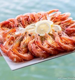 una persona que sosté un plat de gambes amb rodanxes de llimona