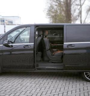 a black van with its door open sitting on a brick road