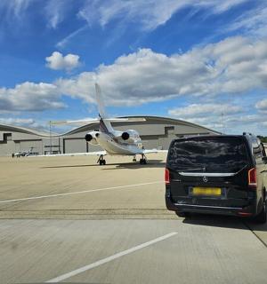 a car parked in front of an airport with a plane