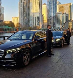 a group of men standing next to a black car