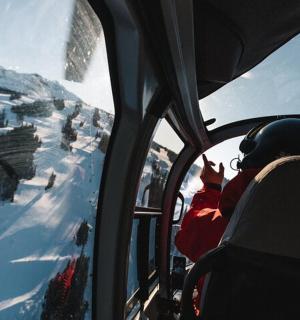 osoba na lyžařské tramvaji dívající se z okna na horu