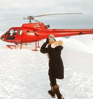 一名男子站在一架红色直升机前