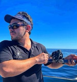 a man holding a camera on a boat in the ocean