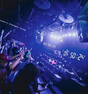 a crowd of people in a club with their hands in the air
