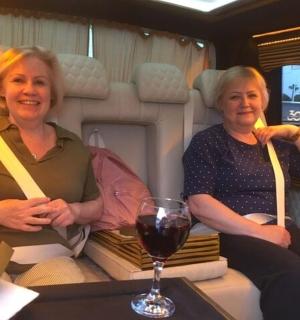 two women sitting in a train with a glass of wine