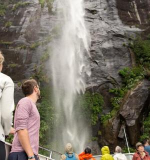 a group of people on a boat looking at a waterfall