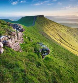 a green hill with rocks on a green field