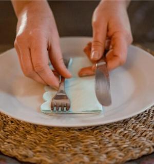 拿着刀叉在盘子上的人