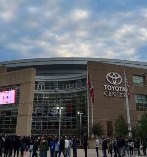 a crowd of people standing outside of a car dealership