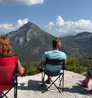 three people sitting in chairs on top of a mountain