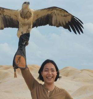 一名女子举着一只展翅的鸟