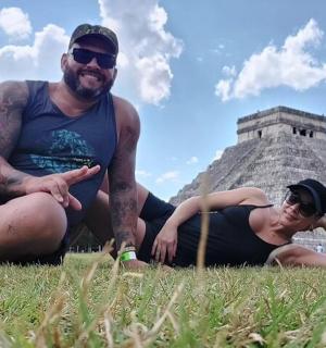 dalawang taong nakaupo sa damuhan sa harap ng pyramid