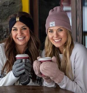 两位女士坐在桌边,手里拿着咖啡杯