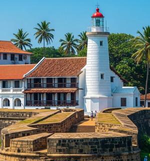 a lighthouse in front of a building with palm trees