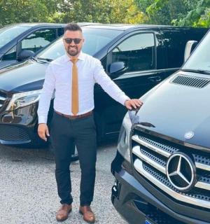 một người đàn ông đeo cà vạt đứng cạnh một chiếc Mercedes Benz