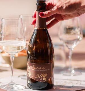 a person opening a bottle of wine on a table with glasses