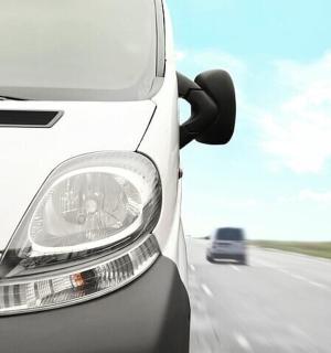 bílá dodávka jedoucí po silnici s autem