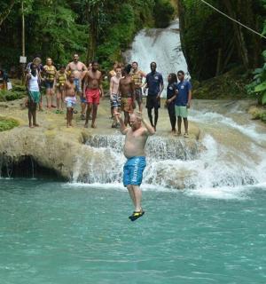 a group of people standing in the water near a waterfall