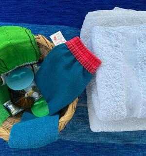 a basket with towels and a hat on a bed