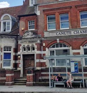 two people sitting on a bench in front of a building