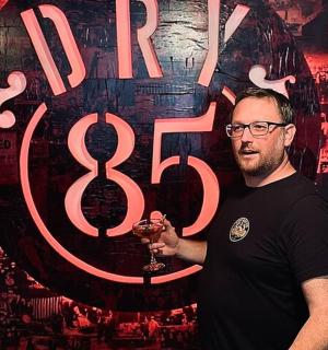 一名男子在标志前举着一杯酒