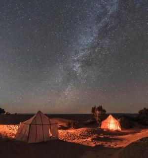 星空下的沙漠中的两个帐篷