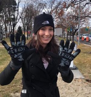a woman is holding up her gloves in a park