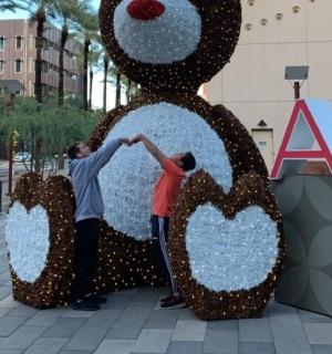 两名男子站在一座大型泰迪熊雕塑旁边