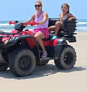 two women riding on a quad bike on the beach