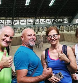 three people giving thumbs up in front of a statue