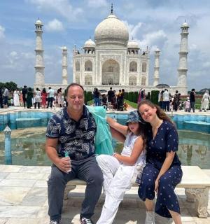 a man and woman sitting on a bench in front of the taj mahal