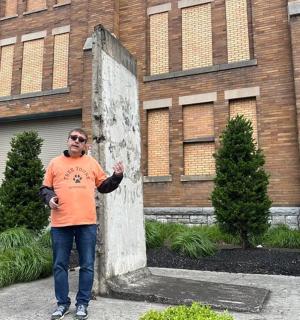 一名男子站在建筑物前的石碑旁