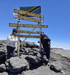 两个人站在海滩上的一块标志牌旁边