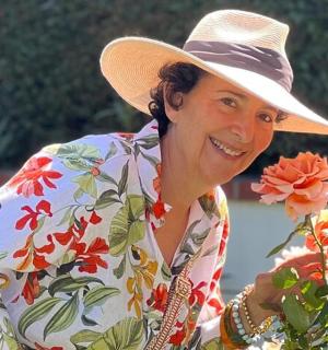 a woman wearing a hat holding a flower