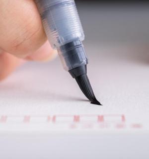a person writing on a piece of paper with a pen