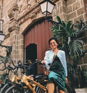 isang babaeng nakaupo sa isang bisikleta sa harap ng isang gusali