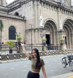 isang babaeng nakatayo sa harap ng isang gusali na nakataas ang kamay