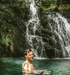 two men in the water near a waterfall