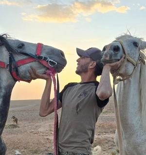 a man standing next to a white horse
