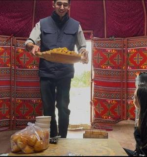 a man holding a tray of food in front of a woman