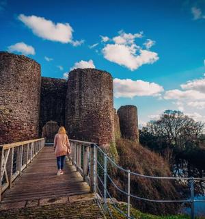 a woman walking down a bridge in front of a castle